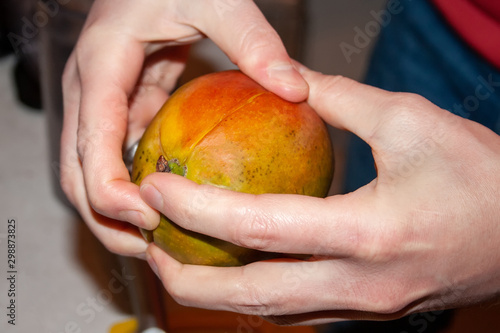 Man's hands divide mango into slices. Selective focus