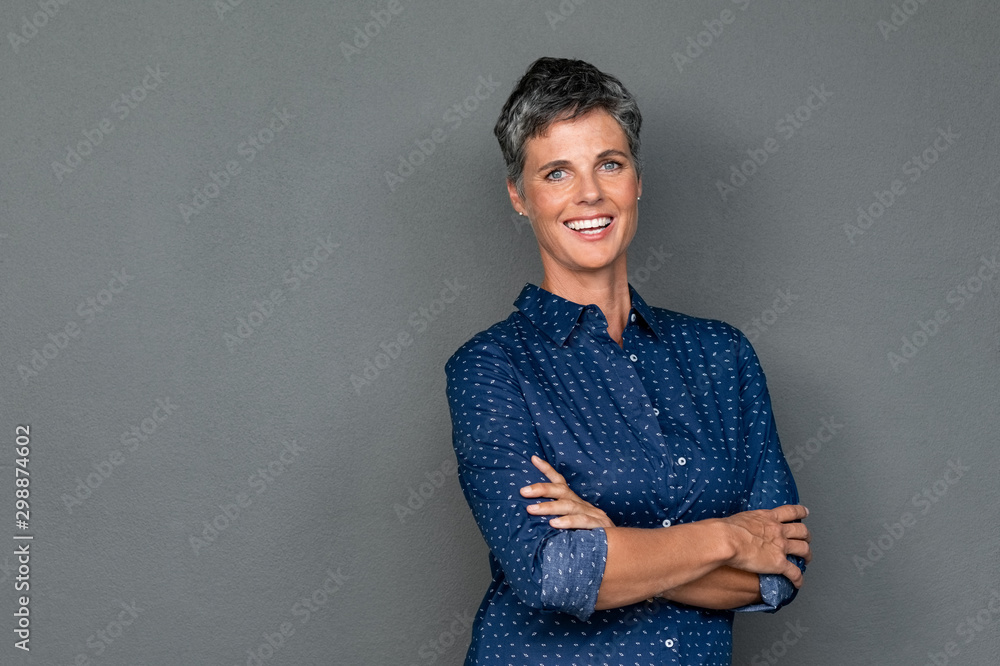 Happy mature woman laughing on grey wall - obrazy, fototapety, plakaty 