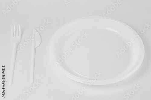 White plastic fork and knife lie to the left of the plate on a white background