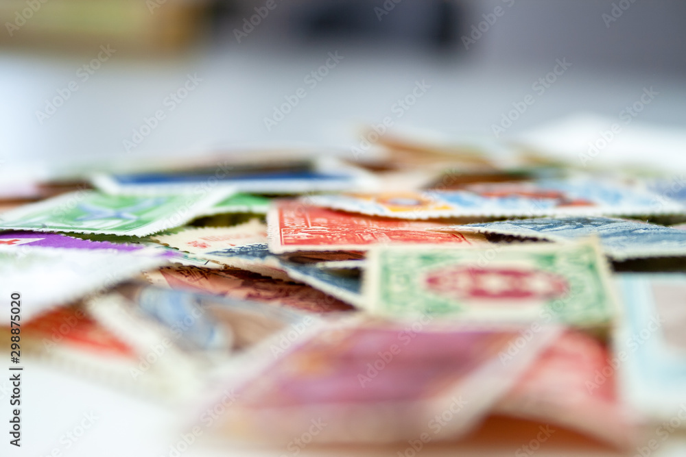 Closeup view on a variety of multi-colored postage stamps from different countries and years. Selective focus Closeup view on a variety of multi-colored postage stamps from different countries and years. Selective focus