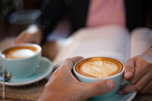 Hand Women and man put a Latte arts coffe hot coffee on wooden table.barista love art concept.