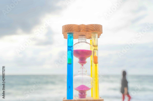 The hourglass passing time on the beach The hourglass in front of the bright blue sky with white clouds passing by Taking pictures in time lapse the concept of time, Phuket Thailand. photo