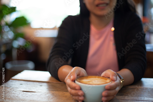 Women reading a book and eating Latte arts coffe hot coffee on wooden table.barista art concept.