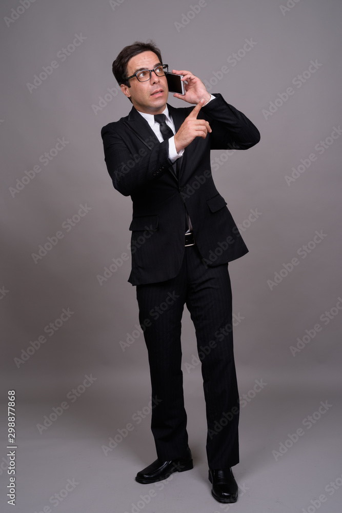 Full body shot of handsome Persian businessman using phone Full body shot of handsome Persian businessman using phone