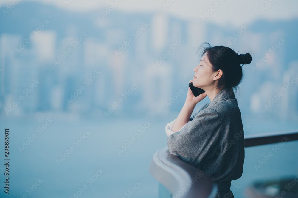 Woman wear bathrobe using smartphone on balcony 