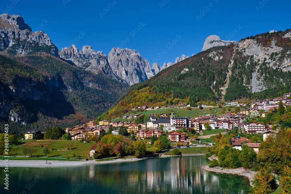 Aerial view of Lake Molveno, north of Italy in the background the city of Molveno, Alps, blue sky. Autumn season. Multi-colored palette of colors