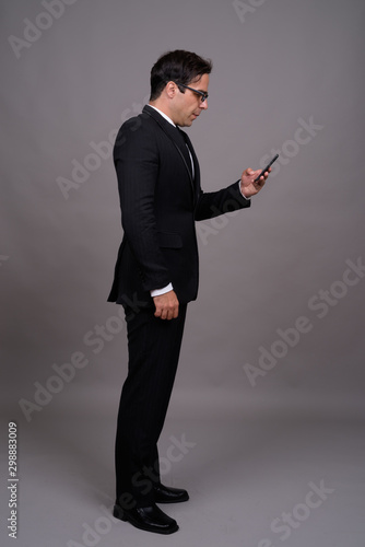 Full body shot of handsome Persian businessman using phone