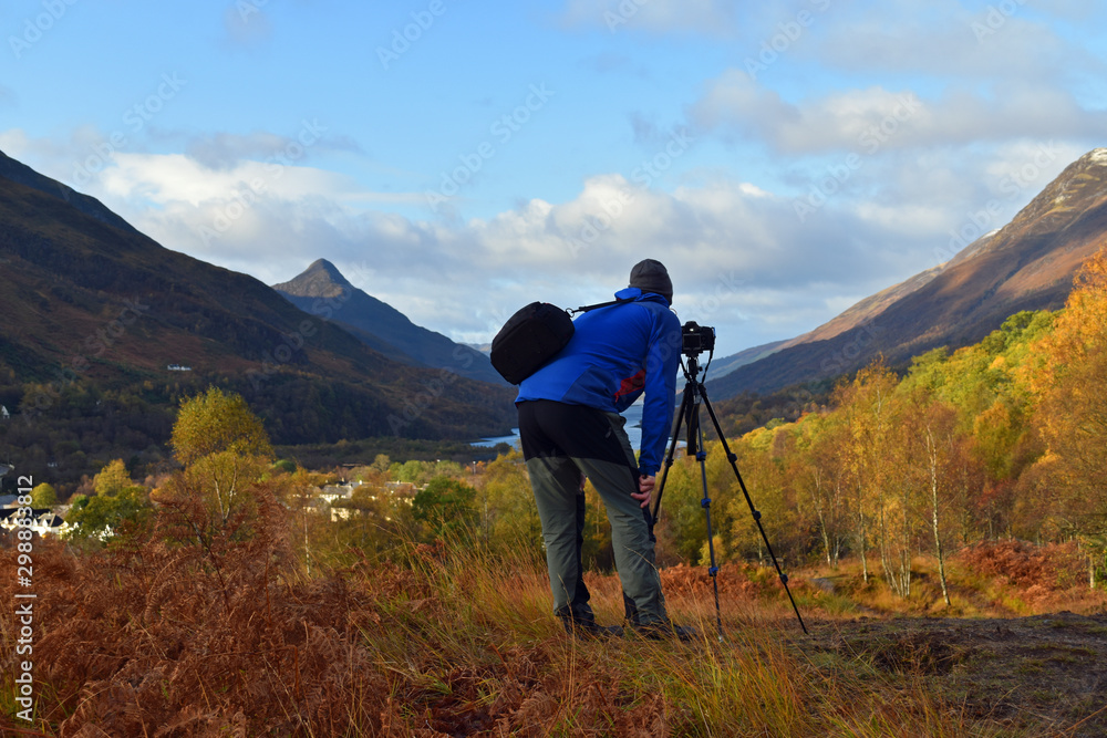 Man taking photograph with tripod at Kinlochleven Scotland looking out over Loch Leven