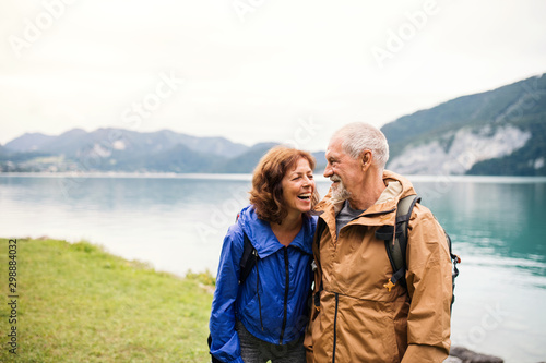 Εκτύπωση καμβά A senior pensioner couple walking by lake in nature, talking.