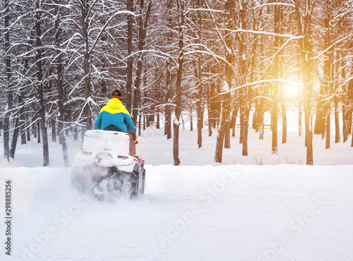 A man rides an ATV in the winter in the forest, the sun, background, copy space
