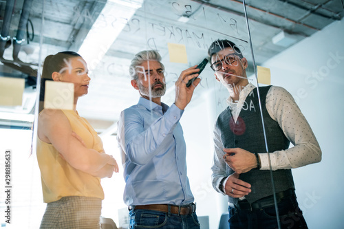 A group of business people standing in an office, brainstorming. photo