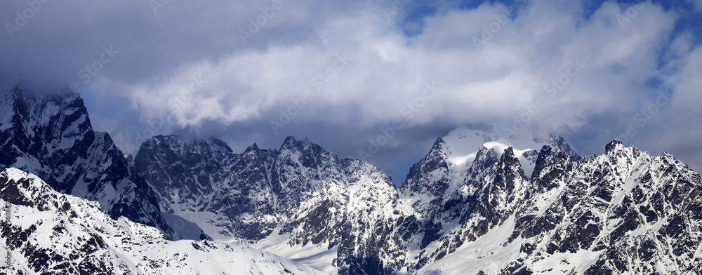 Snowy rocks in clouds at sunny day