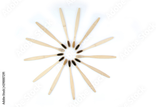 Top view round shaped set of natural wooden bamboo toothbrushes on white background. No plastic and zero waste concept