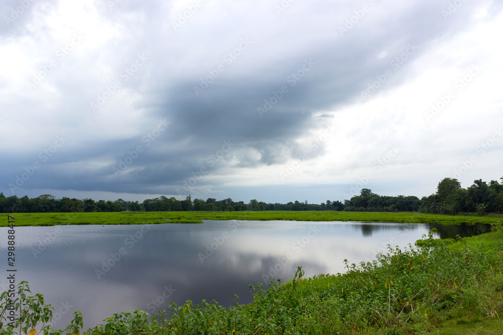 a small lake which reflects the clouds, surrounded by green meadows a small lake which reflects the clouds, surrounded by green meadows