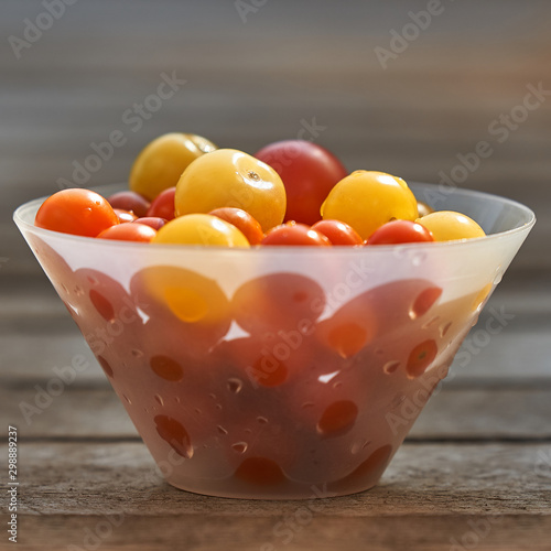 Different sorts of tomatoes served on a white bowl, with wooden background. photo