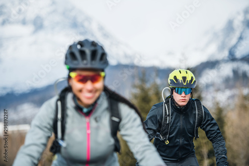 Two mountain bikers riding on road outdoors in winter.