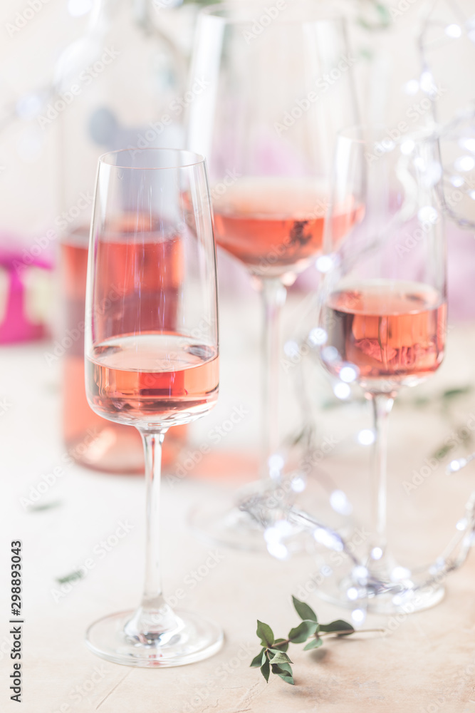 Different glasses and bottle of rose wine on light background.