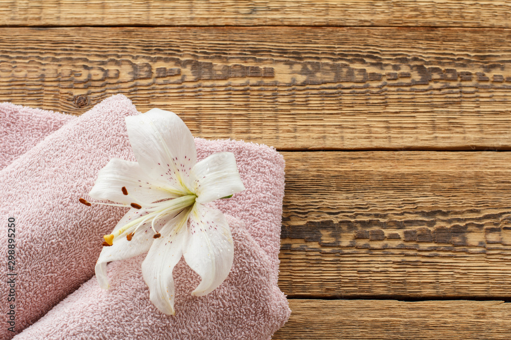 Soft terry towels with lily flower on wooden background. Soft terry towels with lily flower on wooden background.