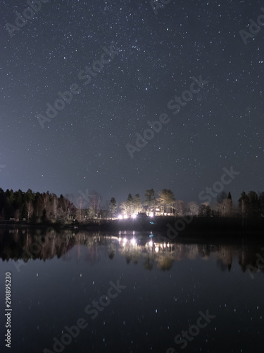 night landscape with lake, house and sky glare in dark water