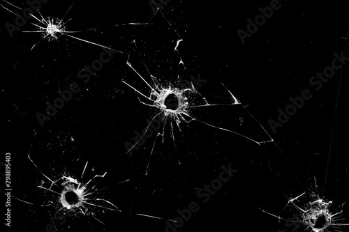 Fototapeta holes in the glass with cracks isolated on a black