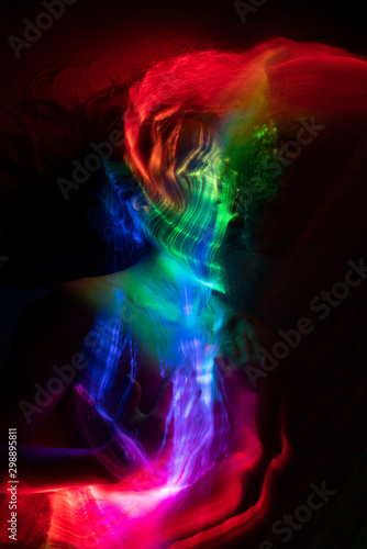 Conceptual avant-garde portrait of a beautiful young girl covered with multicolored lines applied by a light brush. Art style creative photo. Advertising, fashion and commercial design.