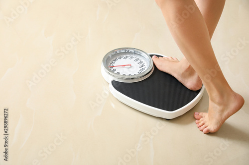 Photography Woman stepping on floor scales indoors, space for text