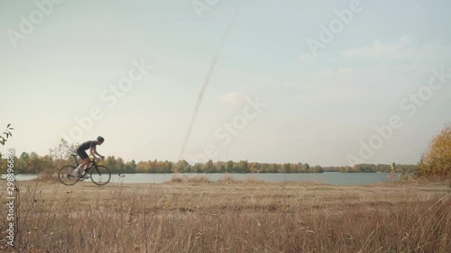 Cyclist Riding On Gravel Bike In Slow Motion.Leader On  Race Hurries To Finish Line.Cycling Race On Gravel Road.Bicycle Racing On Trail. Strong Professional Cyclist Athlete On Crosscoutry Competition  photo