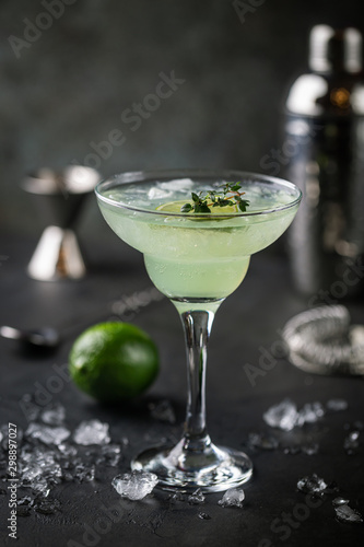 margarita cocktail with lime in a glass on dark background