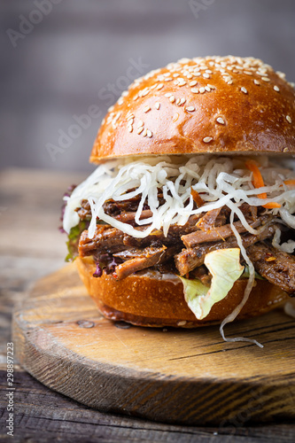 Pulled beef burger with cabbage salad and bbq sauce on cutting board