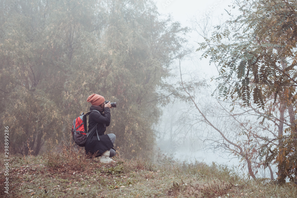 Fototapeta premium Girl photographer takes pictures of autumn nature. 