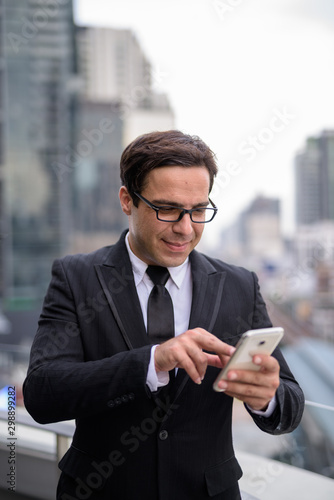 Handsome Persian businessman using phone in the city