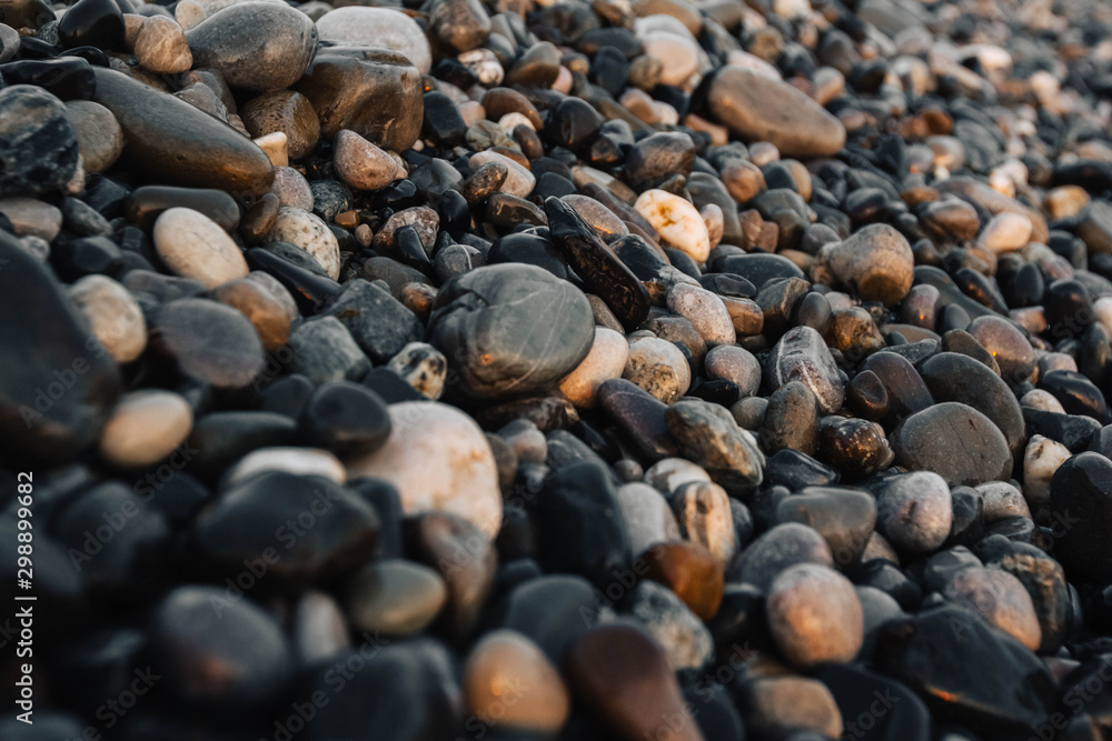 Small stones by the sea with bokeh effect. Blurred decorative background, place for text. Summer wallpaper, sunny sunset light Small stones by the sea with bokeh effect. Blurred decorative background, place for text. Summer wallpaper, sunny sunset light