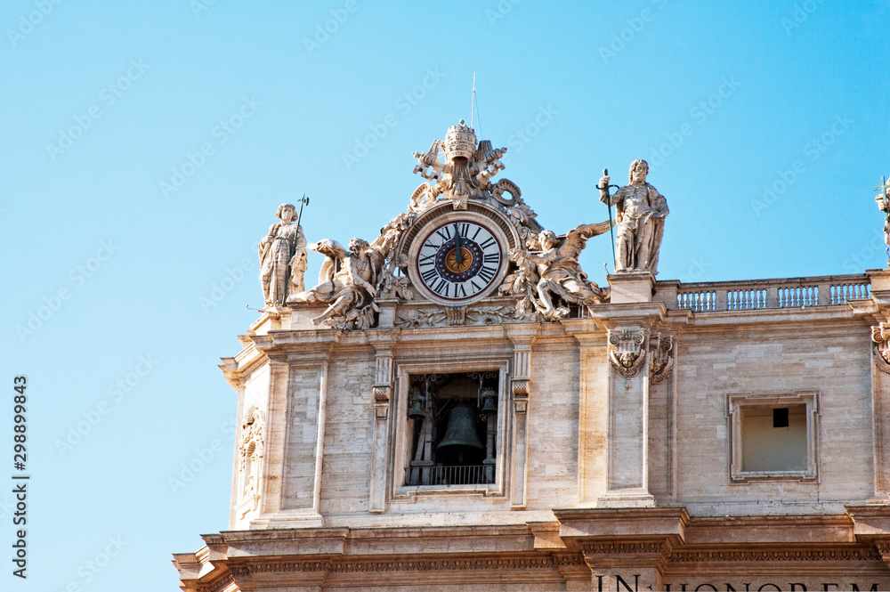 The top-left corner with the clock and the belfry of St. Peter's Basilica's façade, the Vatican. The standing statues are Saints Thaddeus (left) & Matthew (right).