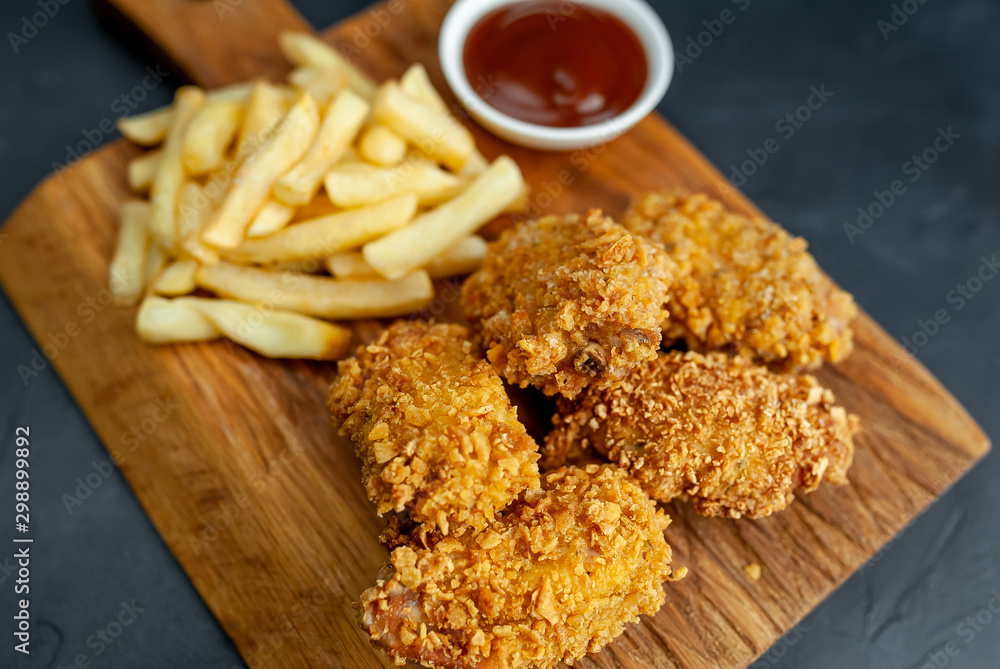 Naklejka premium fried chicken with french fries and food nuggets - on stone background