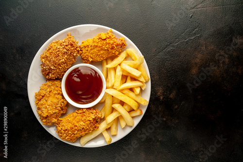 fried chicken with french fries and food nuggets - on stone background