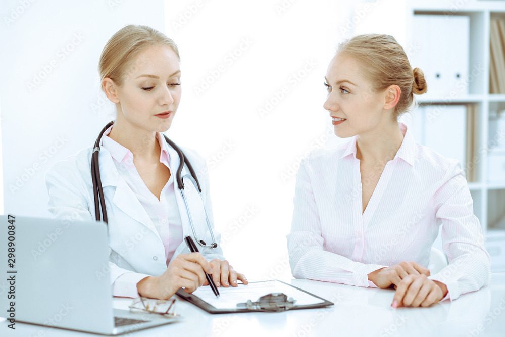 Doctor and patient talking in hospital office while sitting at the desk. Health care and client service in medicine Doctor and patient talking in hospital office while sitting at the desk. Health care and client service in medicine