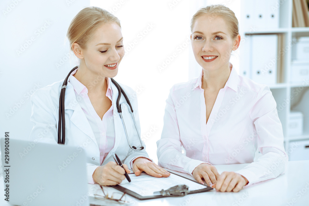 Doctor and patient talking in hospital office while sitting at the desk. Health care and client service in medicine Doctor and patient talking in hospital office while sitting at the desk. Health care and client service in medicine