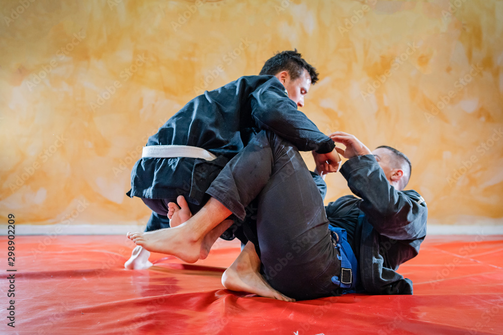 Two brazilian jiu jitsu athletes working on BJJ guard position at the training sparring or drilling fighters at the academy class Two brazilian jiu jitsu athletes working on BJJ guard position at the training sparring or drilling fighters at the academy class