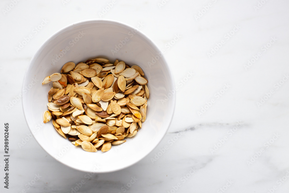 roast Pumpkin seeds in white bowl on marble background with copy space roast Pumpkin seeds in white bowl on marble background with copy space