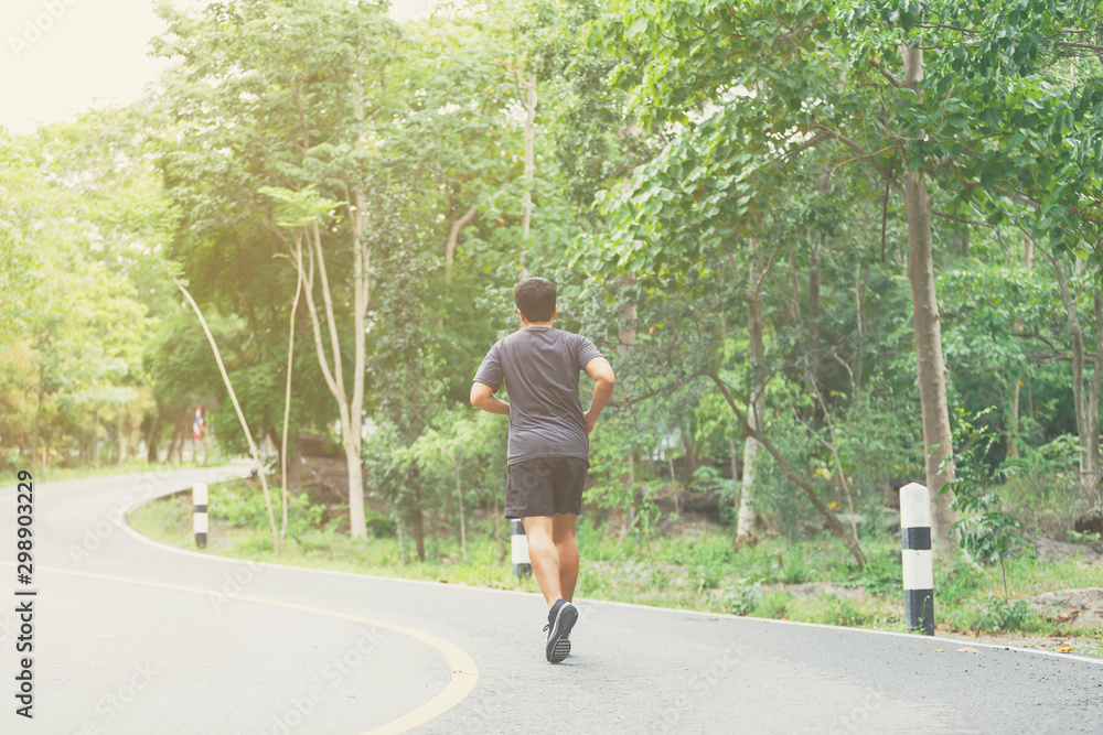 A man running at road surround with green forest.