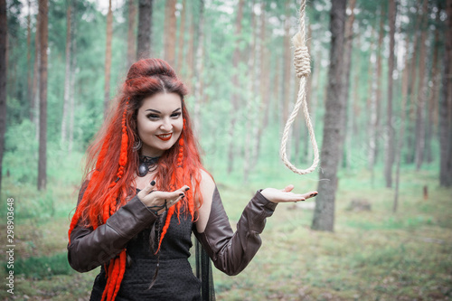 Bild auf Leinwand Beautiful smiling woman witch with hangman loop in the forest
