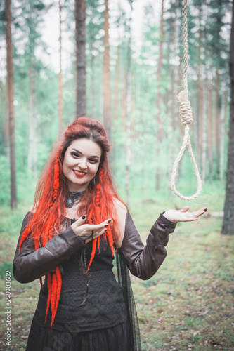 Beautiful smiling woman witch with hangman loop in the forest