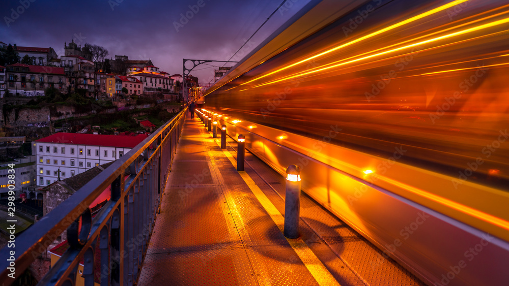 Bright orange traffic light trails of tram crossing the old bridge in Porto. Dynamic motion. Traffic in the city at night Bright orange traffic light trails of tram crossing the old bridge in Porto. Dynamic motion. Traffic in the city at night