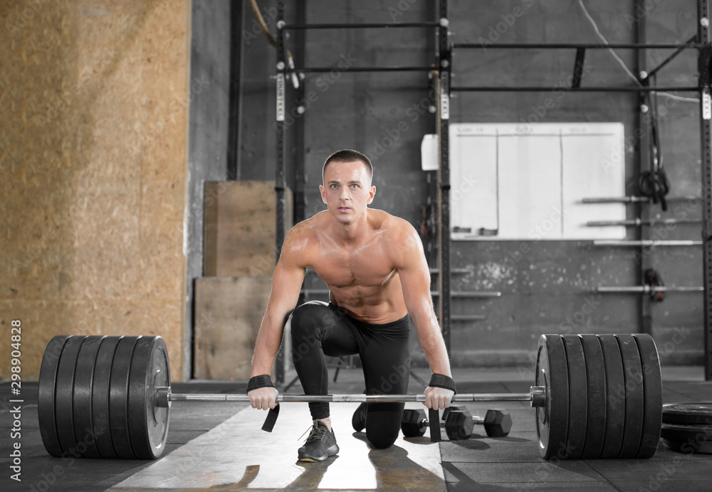 Attractive muscular bodybuilder guy prepare to do exercises with barbell in a gym. Attractive muscular bodybuilder guy prepare to do exercises with barbell in a gym.