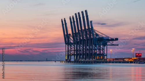 Row of container terminal cranes at red colored sunset in Port of Antwerp, Belgium photo