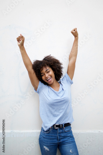 cheerful young african american woman with arms raised photo