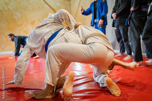 Brazilian jiu jitsu BJJ fighters working on the takedown or judo techniques at the training at academy wearing white kimono gi