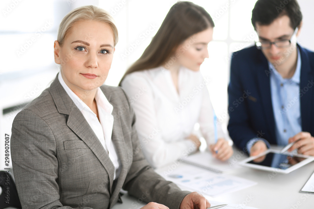 Headshot of business woman at negotiation. Group of business people discussing questions at meeting in modern office. Teamwork, partnership and business concept Headshot of business woman at negotiation. Group of business people discussing questions at meeting in modern office. Teamwork, partnership and business concept