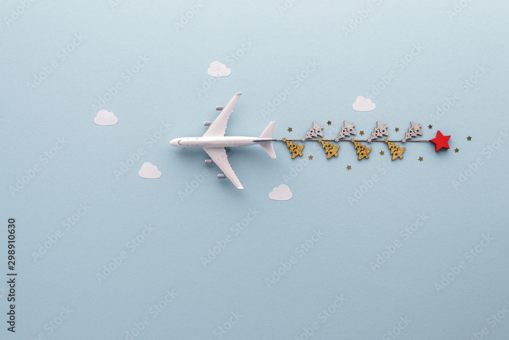 Fototapeta Christmas composition. Airplane flying in sky stars clouds fir top view background with copy space for your text. Flat lay.