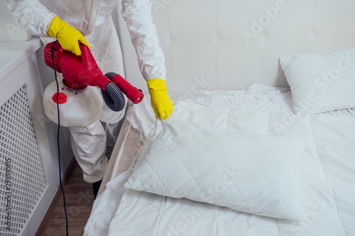 Schilderij op canvas pest control worker lying on floor and spraying pesticides in bedroom